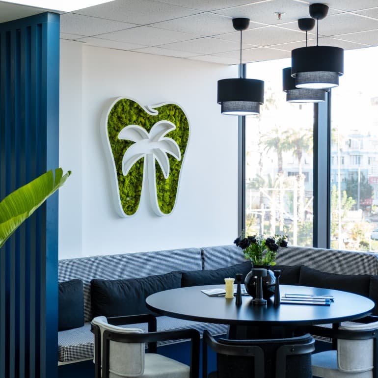 Kącik oczekiwania w klinice Akdeniz Dental w Antalyi z logo zęba na ścianie